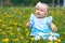 Happy newborn baby in a meadow with yellow dandelions. A toddler playing with soap bubbles in the park