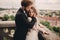 Happy newlywed. beautiful bride and stylish groom are hugging on the balcony of old gothic cathedral with panoramic city views