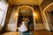 Happy newlywed pair dancing in bright hall with luxurious vintage interior