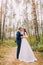 Happy newlywed pair kissing in the autumn pine forest