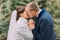 Happy newlywed pair, tender bride and gentle groom, holding hands together while kissing in green park