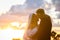 Happy newlyweds hugging against the backdrop of a cloudy sky in the rays of the setting sun