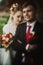 Happy newlyweds portrait, romantic couple, blonde bride with bouquet and handsome groom in stylish black suit posing outdoors, be