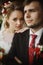 Happy newlyweds portrait, romantic couple, blonde bride with bouquet and handsome groom in stylish black suit posing outdoors, be