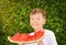 Happy nine years old child boy eating a red juicy watermelon. Caucasian kid smiling and having fun. Concept of healthy food.