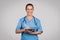 Happy nurse with tablet and stethoscope in scrubs