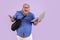 Happy obese man holds cellphone and open laptop on purple background