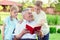 Happy old grandfather reading book for cute children in garden