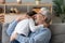 Happy old grandpa embracing little boy grandson cuddling at home