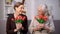 Happy old ladies smiling each other holding red tulips, holiday greeting present