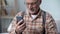 Happy old man holding phone, learning modern technologies, easy app for elderly