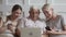 Happy old parents and young daughter using devices talking laughing
