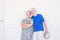 Happy old senior people caucasian couple standing and posing smiling with wooden white wall background - bright image with silver