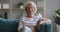 Happy old senior woman looking at camera sit on sofa