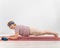 A happy old woman doing a plank on a sports mat. Elderly lady doing fitness exercises on white background.