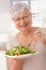 Happy old woman eating green salad