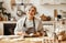 Happy old woman Granny cooks in kitchen kneads dough, bakes cookies