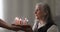 Happy old woman with a gray hair blowing candles on a cake.