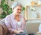 Happy old woman senior working at computer laptop at home