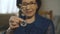 Happy old woman shows a silver bitcoin for camera and smiling