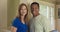 Happy older Caucasian and African American couple standing in their home smiling