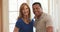 Happy older Caucasian and African American couple standing in their home smiling