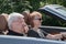 Happy older couple drives with a luxury convertible car
