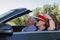 Happy older couple drives with a luxury convertible car