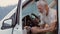 Happy older man traveler sitting in camper van using mobile in camping.