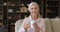 Happy older woman sit on sofa at home with teacup