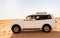 Happy Omani man in traditional cloth driving the white offroad 4x4 car in the Wahiba Sands Desert