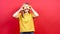 Happy, optimistic girl in a yellow T-shirt, covering her eyes with lemon,