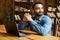 Happy and optimistic Indian man in casual wear using laptop