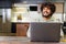 Happy and optimistic Indian man in casual wear using laptop in modern flat. Successful inspired Arabic male entrepreneur