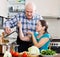 Happy ordinary mature couple cooking lunch