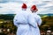 Happy Ñouple in a white coat and Santa Helper Hats on the mountain