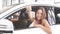 Happy overjoyed brunette female new car owner sitting in white car and demonstrates the key