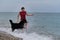Happy owner of Bernese Mountain Dog on vacation on beach. Caucasian cute red haired woman in swimsuit runs around sea with her