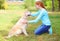 Happy owner woman stroking Golden Retriever dog on grass