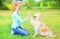 Happy owner woman training Golden Retriever dog on grass