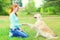 Happy owner woman training Golden Retriever dog on grass in park
