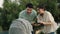 Happy parent (father and mother) talking and playing with infant baby in stroller while resting in park