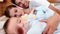 Happy parents lying on bed with baby son