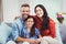 Happy parents sitting with daughter on sofa