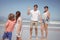 Happy parents waving hands while looking at children standing on shore