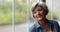 Happy peaceful older woman looking out of window.