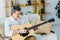 Happy pensioner in glasses playing acoustic guitar