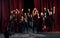 Happy people celebrating success. Group of actors in dark colored clothes on rehearsal in the theater