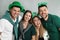Happy people in St Patrick`s Day outfits on light grey background