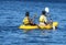 Happy people swimming in kayaks wearing lifejackets with paddle